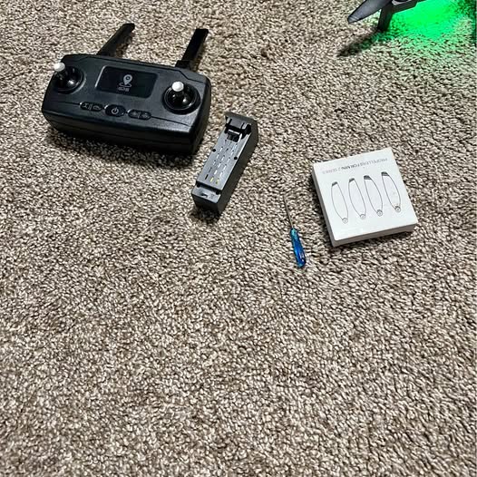 Black GPS drone controller with detachable antenna and accessories on carpet