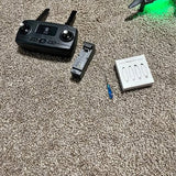 Black GPS drone controller with detachable antenna and accessories on carpet