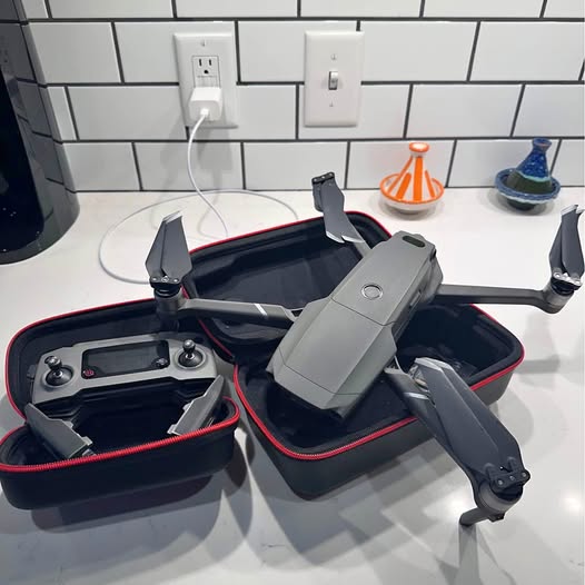 Folding quadcopter drone, gray body with four propellers, in open carrying case