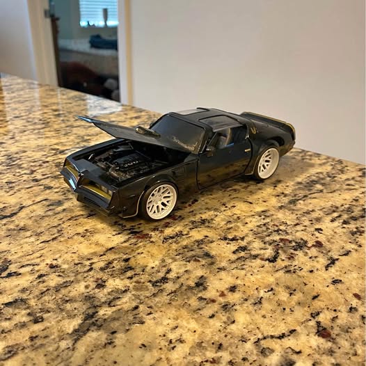 Black diecast sports car model, front three-quarter view, open hood detail