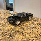 Black diecast sports car model, front three-quarter view, open hood detail