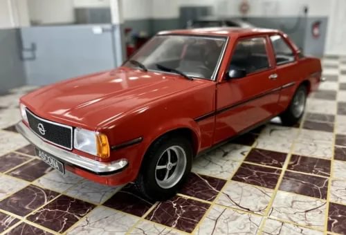Red diecast model car, front 3/4 view, chrome bumper and grille, amber headlights