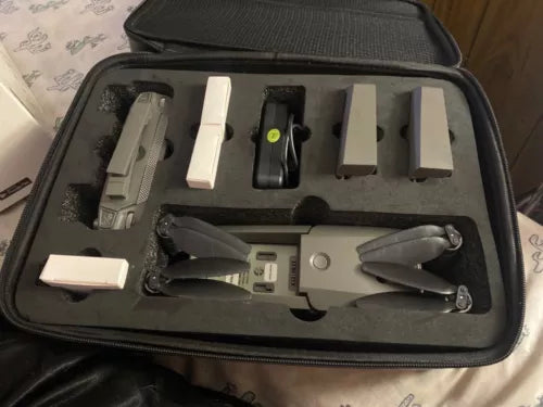 Foldable camera drone kit in carrying case with propellers, batteries, and remotes