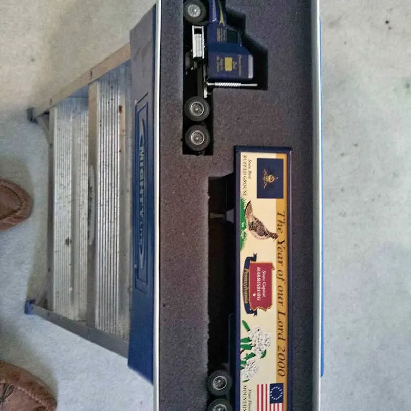 Diecast truck model in box, blue and black with visible wheels