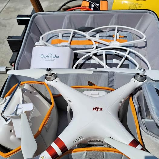 White quadcopter drone with orange accents and four arms, propellers visible