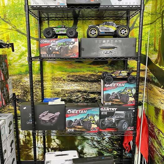 Stacked RC drone and car boxes on a black metal display rack