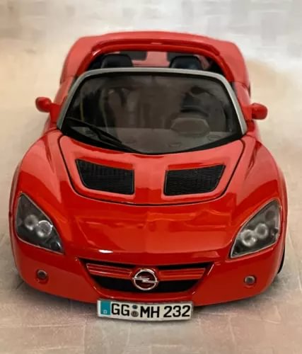 Orange-red convertible diecast car front view with hood scoop and grille