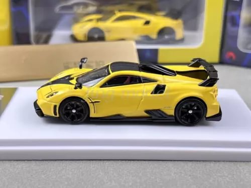 Yellow sports model diecast car with black wheels and rear spoiler, side view