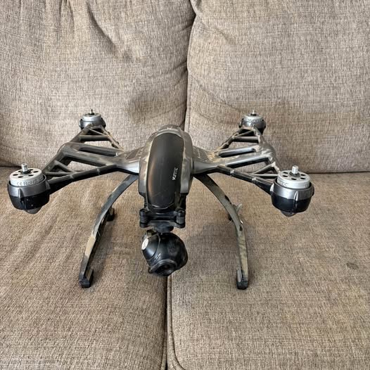 Quadcopter drone with four rotors, dark gray body and front camera module