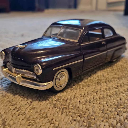 Diecast classic car model in dark metallic black, with chrome front bumper