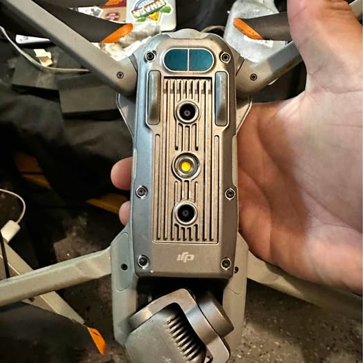 DJI drone body close-up with vents, ports panel, and gimbal arm
