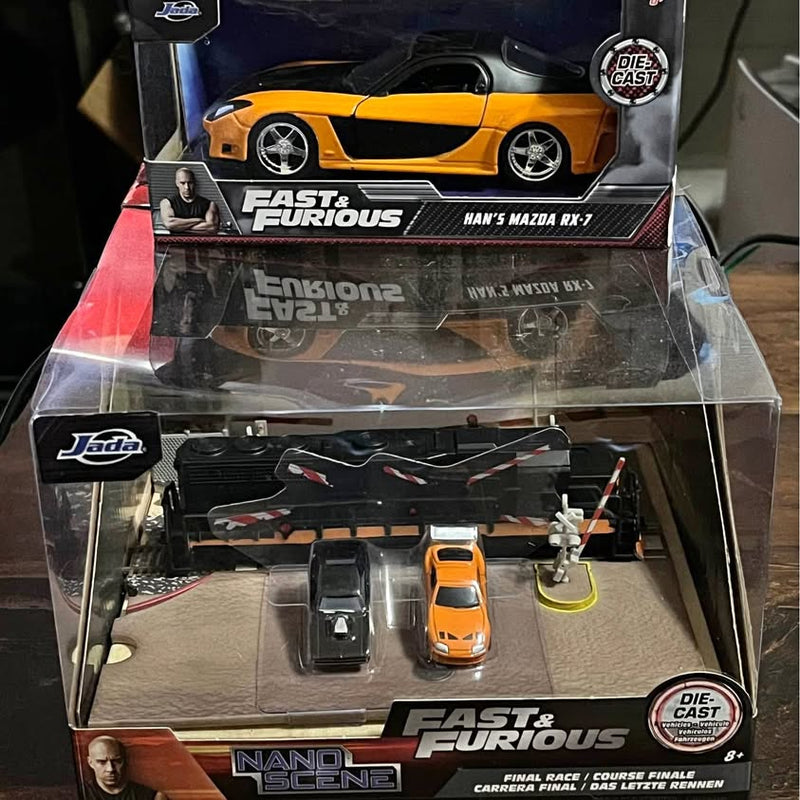 Die-cast toy car playset with orange and black cars in a clear display case