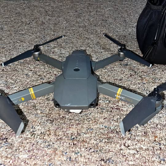 DJI Mavic Pro drone with four propellers, body and arms visible on ground