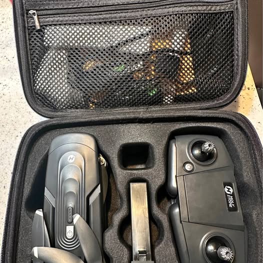Gray drone and controller in hard case with compartments and accessory pieces