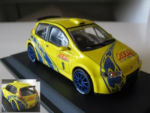 Yellow 1/43 diecast rally car with blue wheels, detailed decals and front view.
