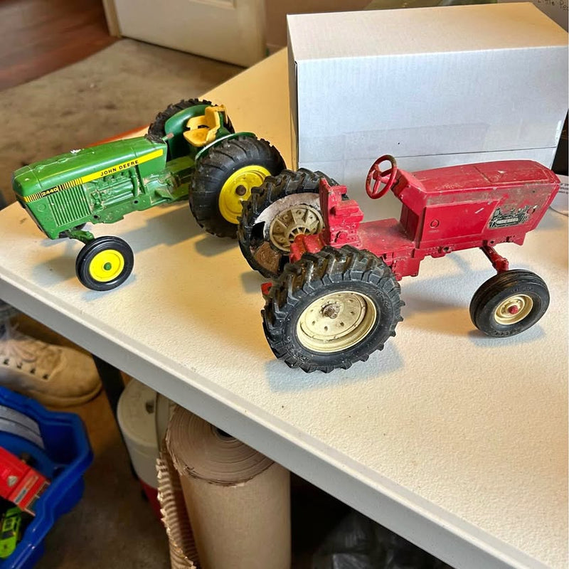 Vintage diecast tractor toys: green, yellow, and red with wheels, on display