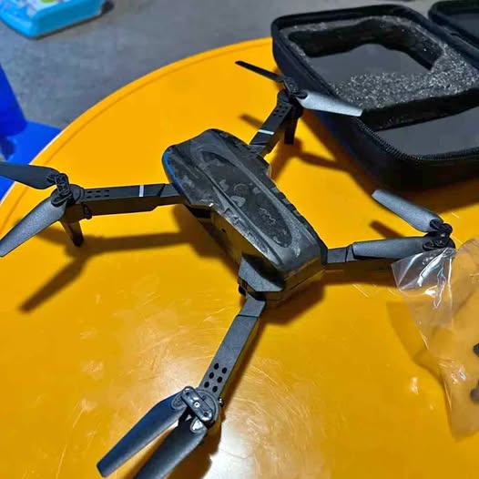 Gray quadcopter drone with mounted camera and four propellers, folded arms