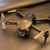 Foldable quadcopter drone with camera and propellers, dark gray body