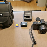 Nikon 1 V1 digital camera with attached lens and neck strap, gray body