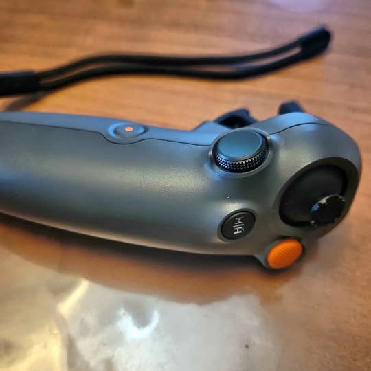 Blue-gray drone controller with thumb wheel and orange trigger