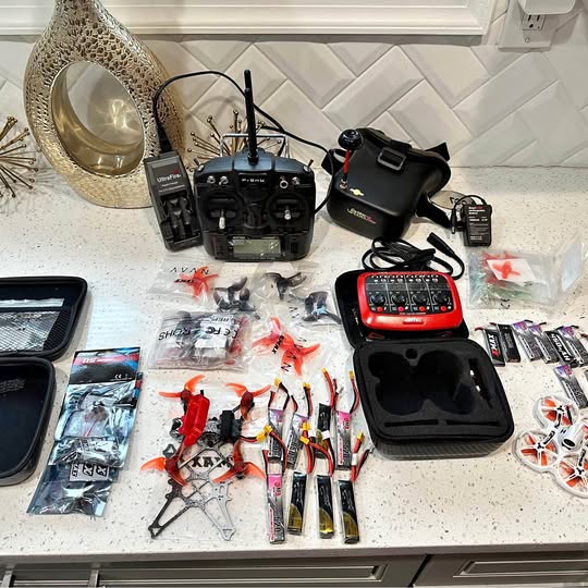 FPV drone accessories kit with transmitter, goggles, batteries, and spare parts