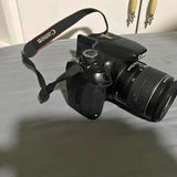 Black camera with shoulder strap and large zoom lens
