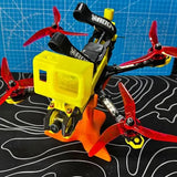 FPV racing drone with yellow housing, red propellers, and camera module