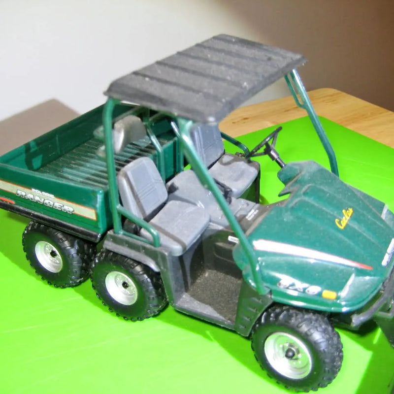 Green 1/18 scale diecast car with open flatbed loaded with gray blocks and spare tires