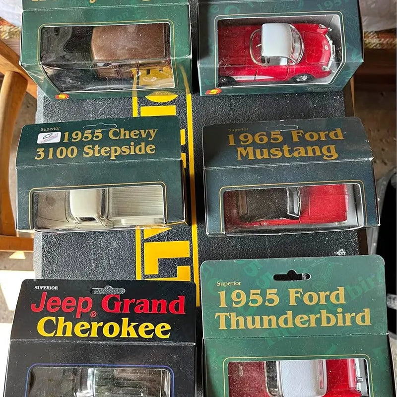 Diecast toy vehicle boxes with classic car models: Chevy 3100, Mustang, Jeep Cherokee, Thunderbird