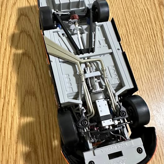 Diecast race car chassis with exposed silver engine and black wheels