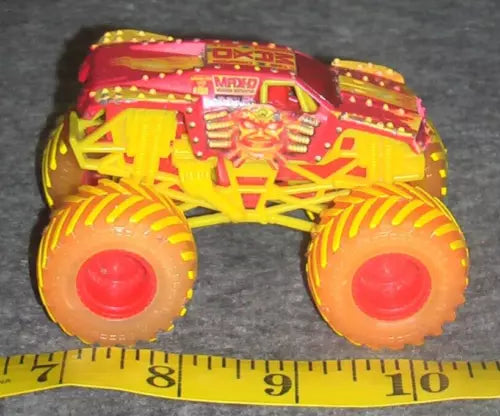 Yellow and red flame monster truck diecast with oversized orange wheels, front view.