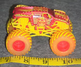Yellow and red flame monster truck diecast with oversized orange wheels, front view.