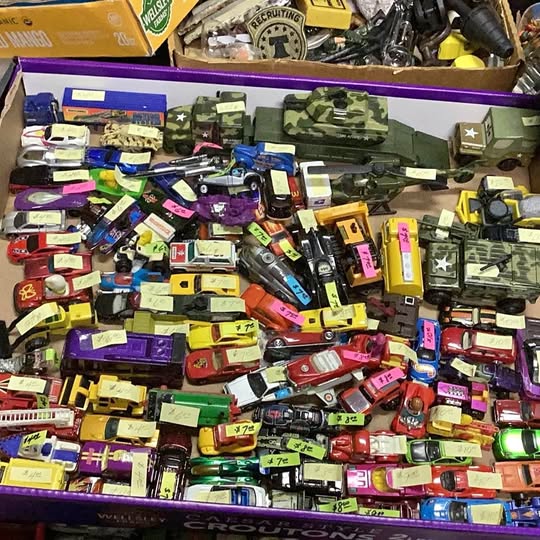 Assorted diecast toy vehicles in mixed colors and styles, in a display bin