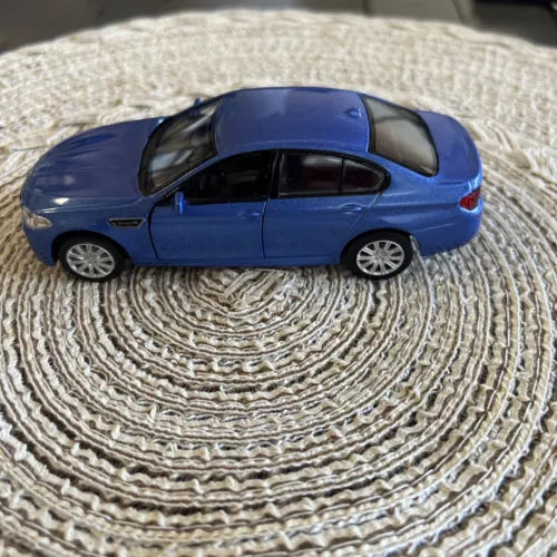 Blue diecast model car with pullback action, side view, silver wheels, detailed windows