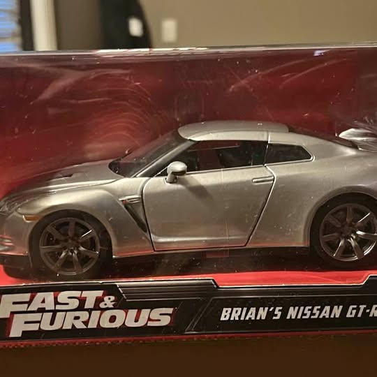 Silver diecast sports car model with black wheels and side profile view