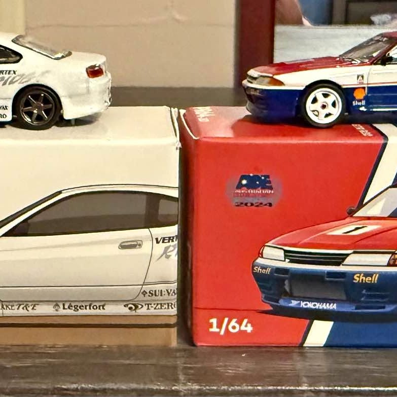 Diecast model car in box, red and blue 1/64 scale, front corner view