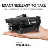 Foldable black quadcopter drone with camera and front sensors, folded on hand