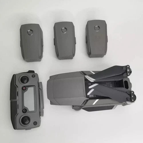 Grey foldable quadcopter drone with propellers and three spare batteries