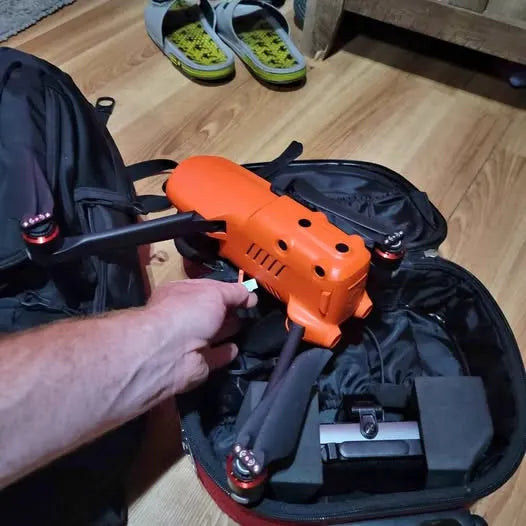 Orange and black quadcopter drone with prop arms in a carrying case