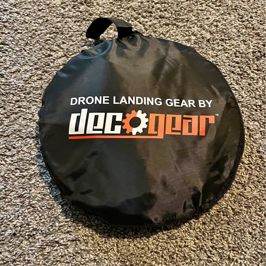 Black circular drone landing gear with drawstring bag and logo text