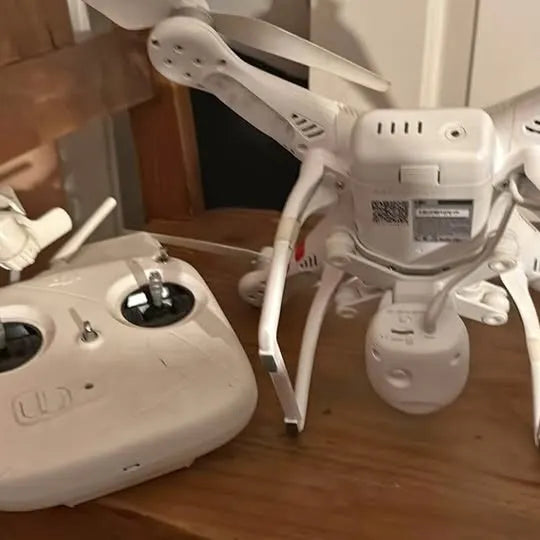 White DJI drone with four propellers, top and controller mounts visible