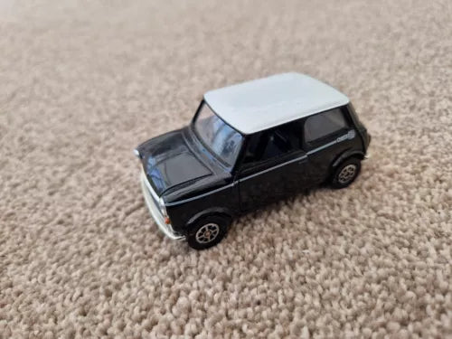 Black diecast mini car model with white roof, side view