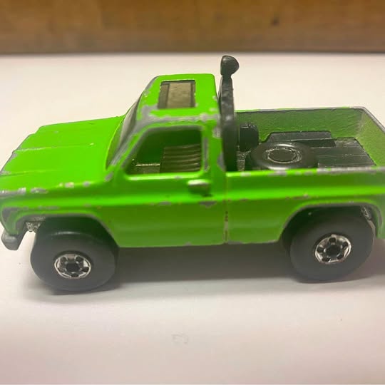 Green Hot Wheels diecast pickup truck with black details and silver wheels