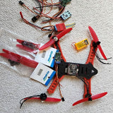 Mini quadcopter parts set with red propellers, circuit boards and wiring