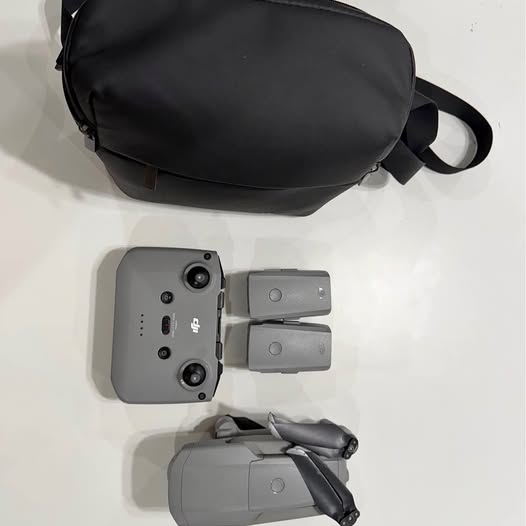 Drone with gray controller and gray carrying case, seen from above