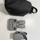 Drone with gray controller and gray carrying case, seen from above