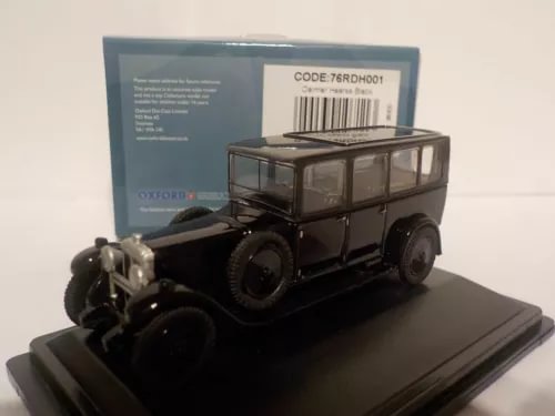 Black diecast model hearse car on display base, front three-quarter view