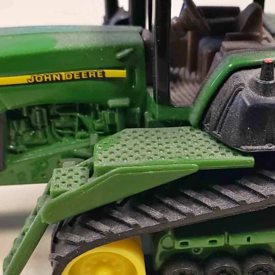 Green diecast tractor toy with black engine and yellow wheel detail