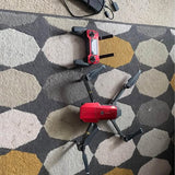 Red and black foldable quadcopter drone with camera, four rotors, on ground