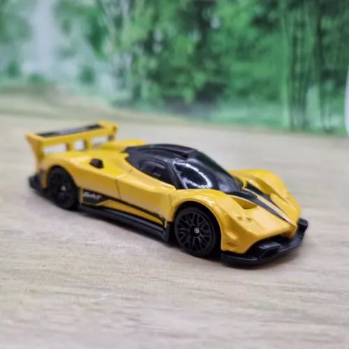 Yellow and black diecast race car model with black hood stripe, 1/64 scale.